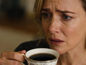 Jeune femme européenne avec une expression inquiète tenant une tasse de thé noir dans une lumière naturelle douce