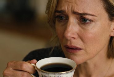 Jeune femme européenne avec une expression inquiète tenant une tasse de thé noir dans une lumière naturelle douce