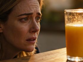 Femme d'âge moyen avec une expression inquiète tenant un verre de jus d'orange devant elle, éclairage naturel
