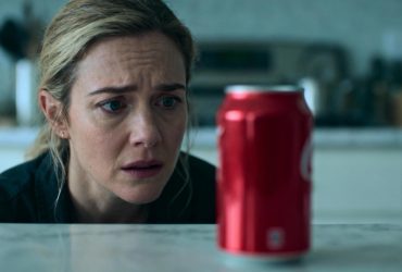 Femme européenne préoccupée regardant une canette de coca-cola posée sur un plan de travail de cuisine