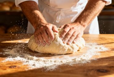 Boulanger européen préparant du pão doce brésilien sur une table en bois avec farine et lumière naturelle