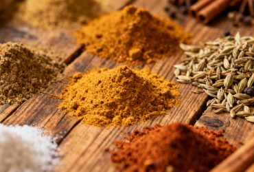 Chef européen préparant des alternatives au curry sur une table en bois rustique, avec des épices disposées en petits bols