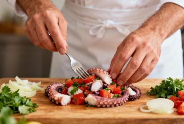 Chef professionnel préparant une salade de poulpe portugaise avec des ingrédients frais dans une cuisine