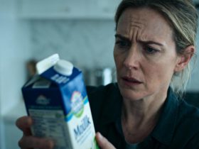 Femme européenne d'âge moyen examinant attentivement un carton de lait dans une cuisine moderne