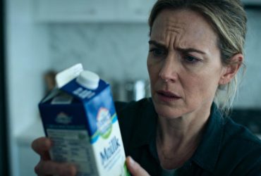 Femme européenne d'âge moyen examinant attentivement un carton de lait dans une cuisine moderne