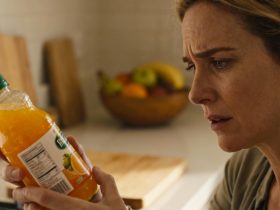 Femme européenne préoccupée lisant attentivement les informations nutritionnelles sur une bouteille d'orangeade dans sa cuisine