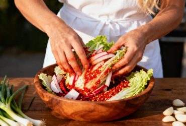 Femme européenne préparant du kimchi coréen avec des légumes frais dans une cuisine lumineuse